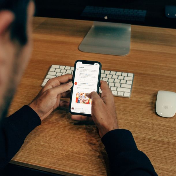 Mann mit Smartphone am Schreibtisch